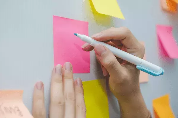 Woman writing on a post-it note